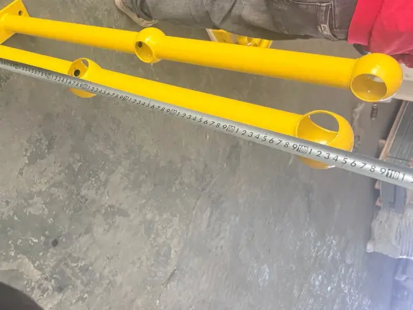 Worker is measuring the length of grating ball joint stanchions with a tape.